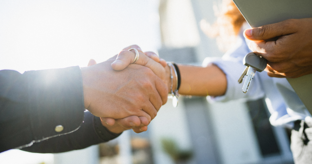 Handshake between a homebuilder CEO and a brokerage and marketing agency CEO.